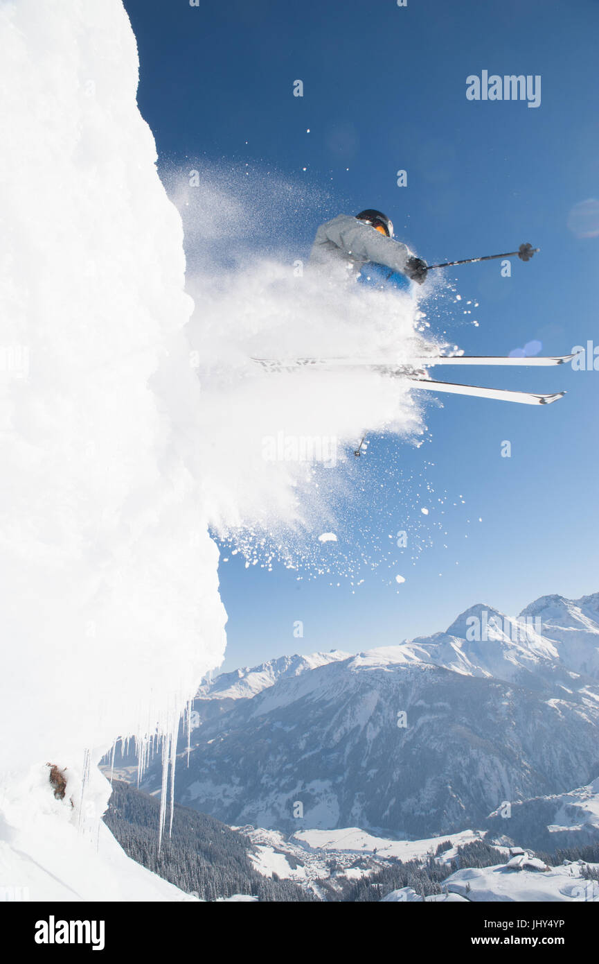 Sciatore andando su una scogliera trailing uno spruzzo di neve Foto Stock