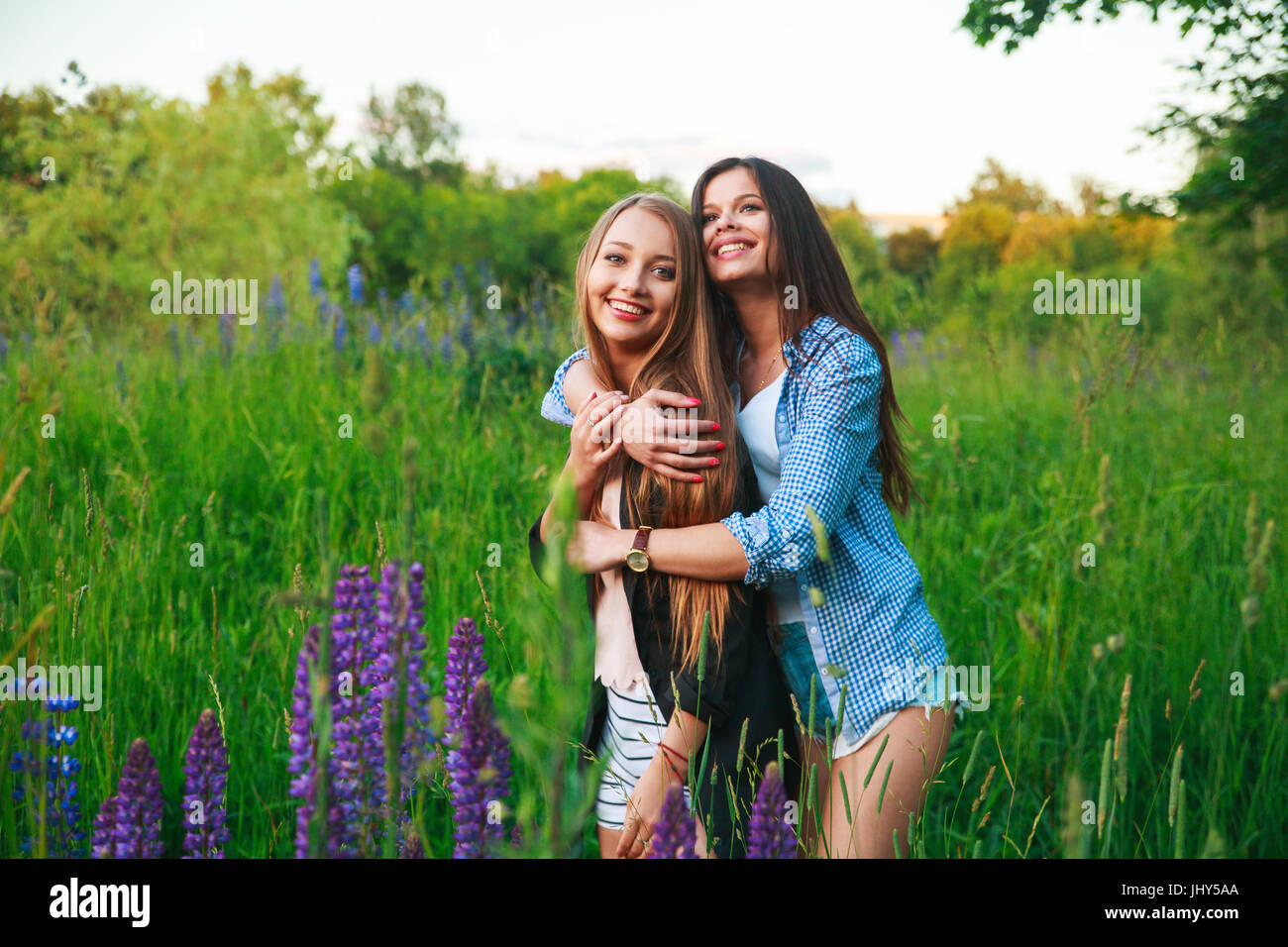Amiche amicizia felicità nozione comunitaria. Due amici sorridenti abbracciando all'esterno. Foto Stock