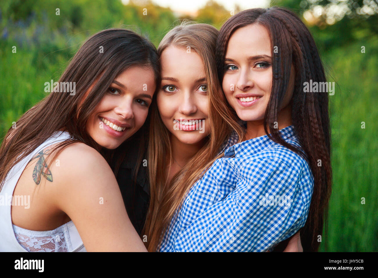 Amiche amicizia felicità nozione comunitaria. Tre amici sorridente abbracciando all'aperto nella natura Foto Stock