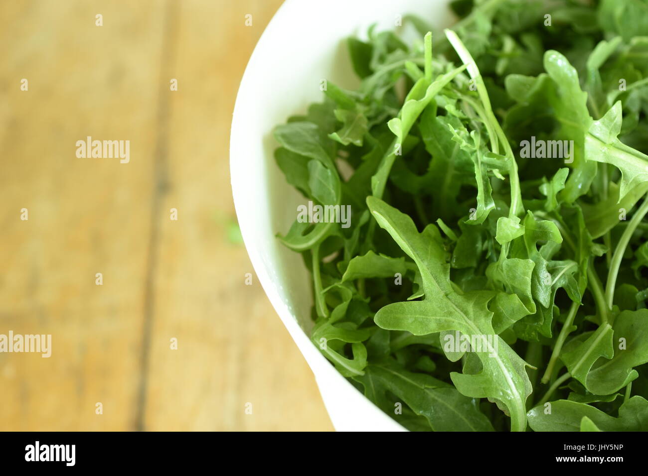 Close-up su un mazzetto di rucola fresca di foglie in una ciotola bianco Foto Stock