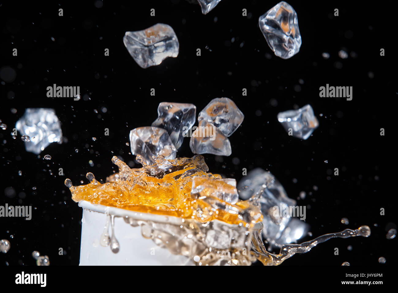 Cristalli di ghiaccio che cadono in limonata su un nero di sfondo per studio Foto Stock