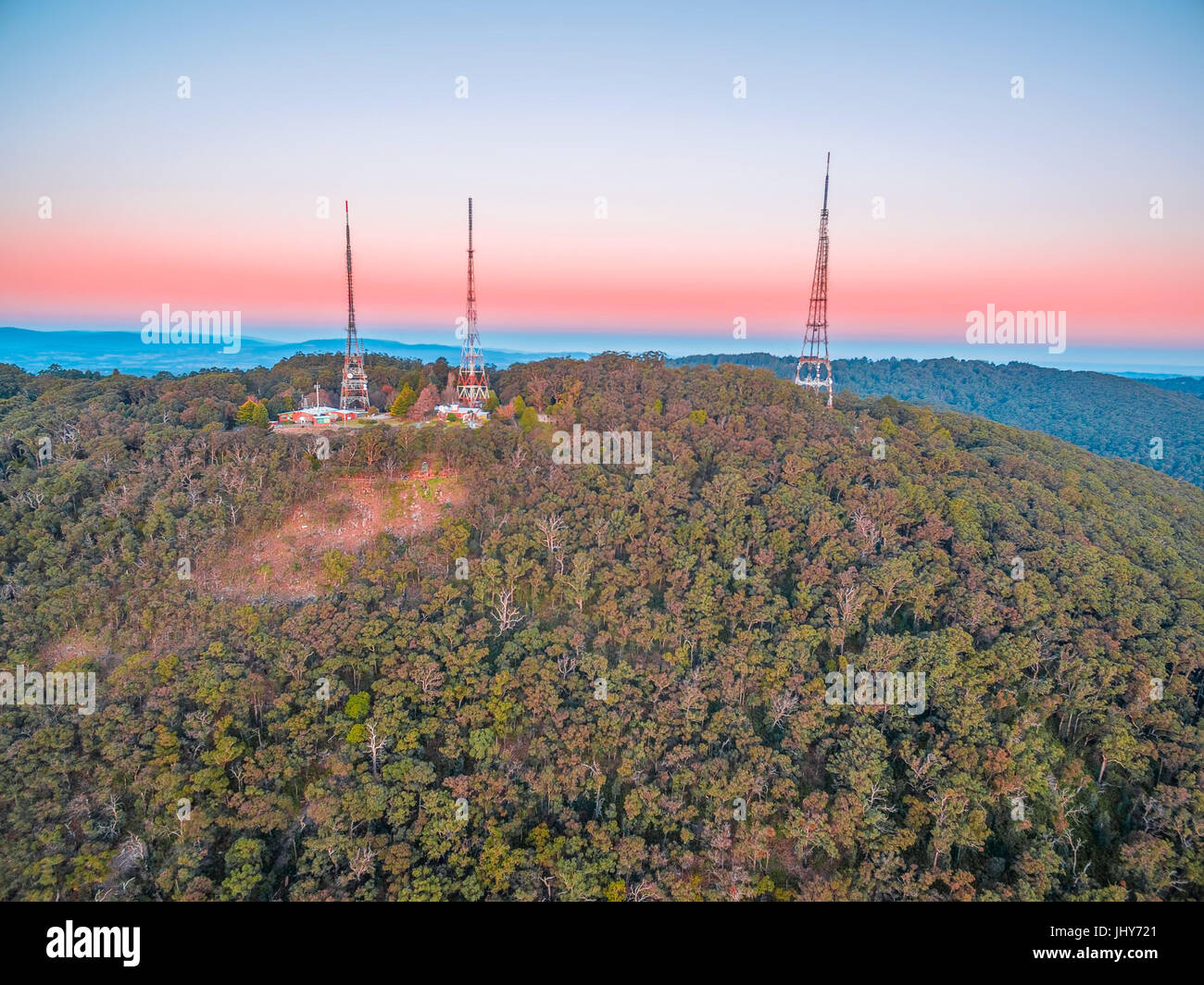 Vista aerea di tre torri della televisione antenne sulla parte superiore della foresta di eucalipti collina al tramonto. Foto Stock