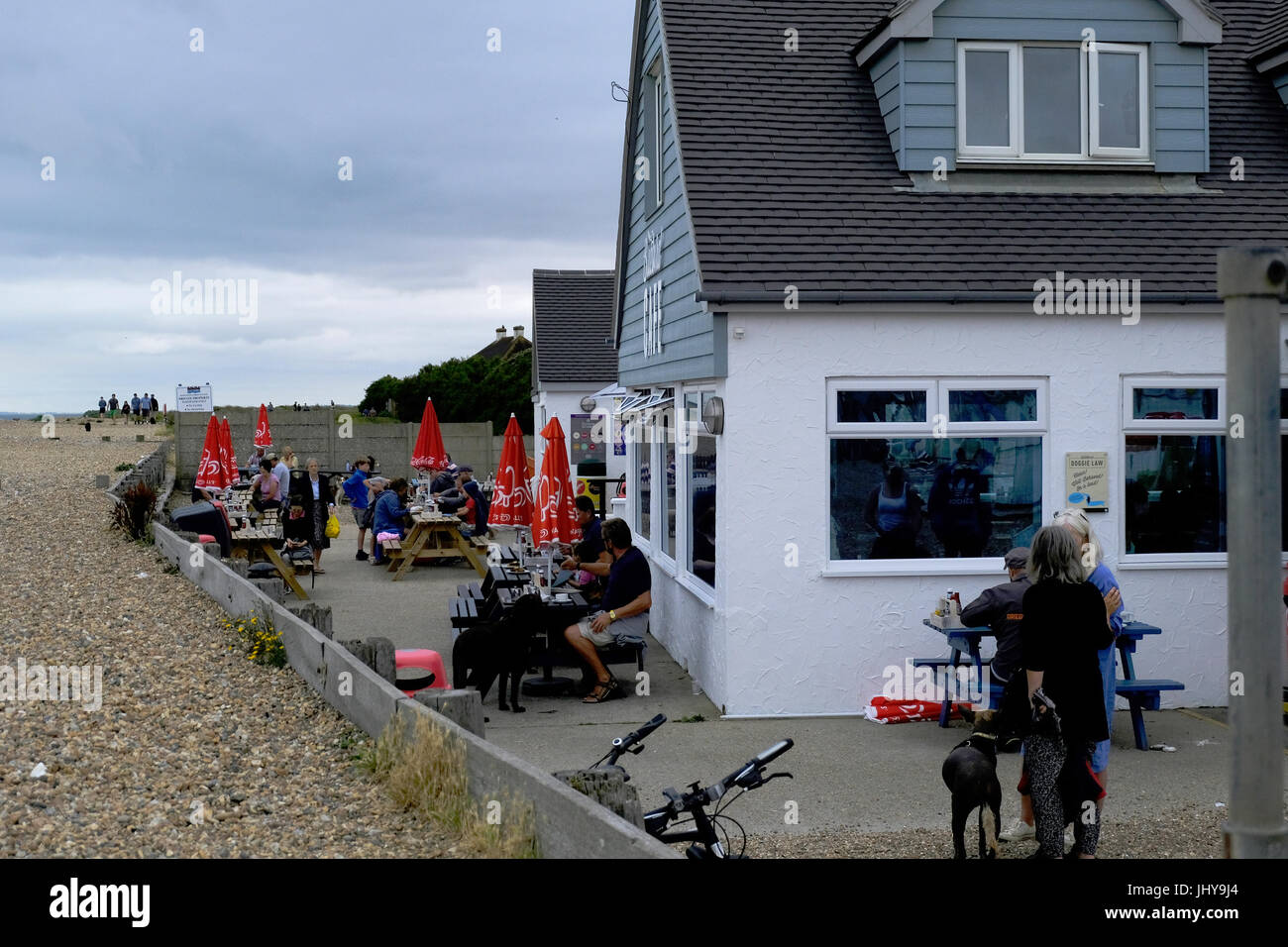 I villeggianti avente inizio il caffè di mattina su una grigia mattina nuvoloso presso il beach bar sulla spiaggia Ferring, vicino a Worthing, West Sussex, Regno Unito Foto Stock
