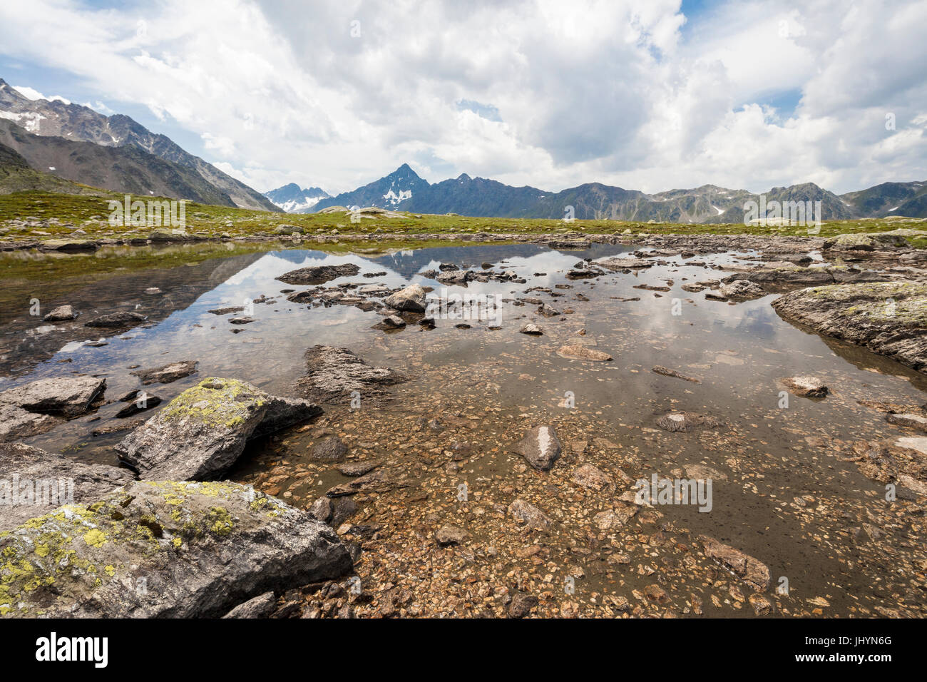 Nuvole su picchi rocciosi riflessa nel lago alpino Schottensee, Fluela Pass del cantone dei Grigioni, Engadina, Svizzera, Europa Foto Stock