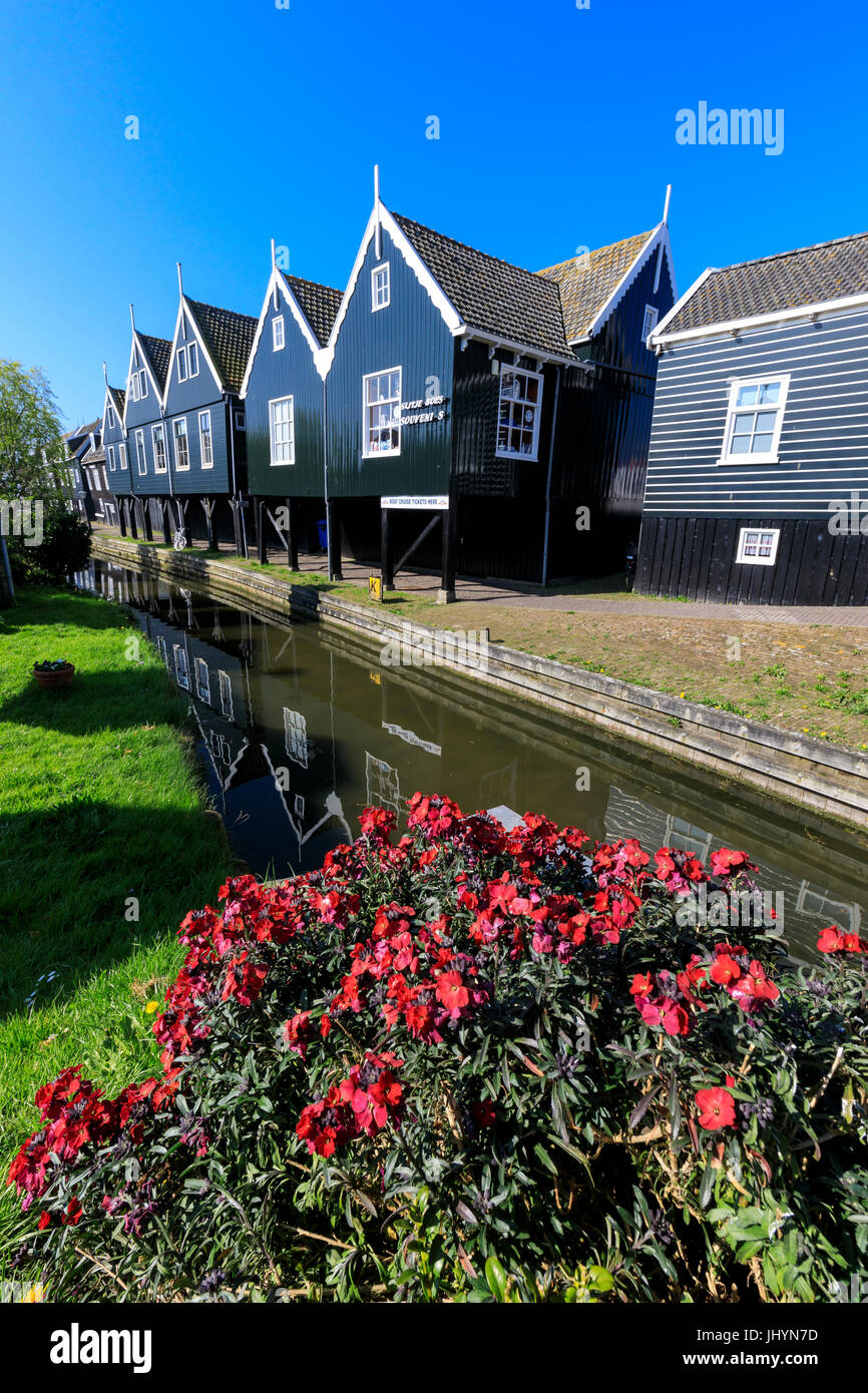 Case di legno si riflette nel canale incorniciato da fiori nel villaggio di Marken, Waterland, North Holland, Paesi Bassi Foto Stock