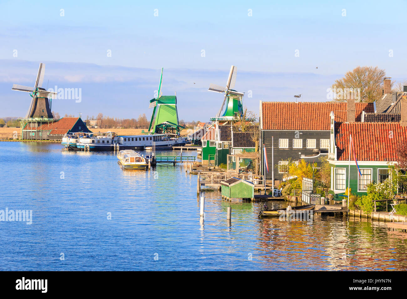 Case di legno e di un mulino riflessa nelle acque blu del fiume Zaan, Zaanse Schans, North Holland, Paesi Bassi, Europa Foto Stock