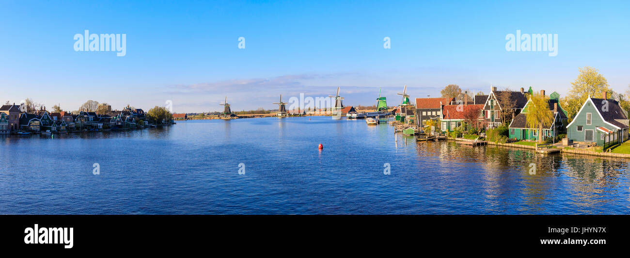 Panorama di case di legno e mulini a vento incorniciato dal blu fiume Zaan, Zaanse Schans, North Holland, Paesi Bassi, Europa Foto Stock