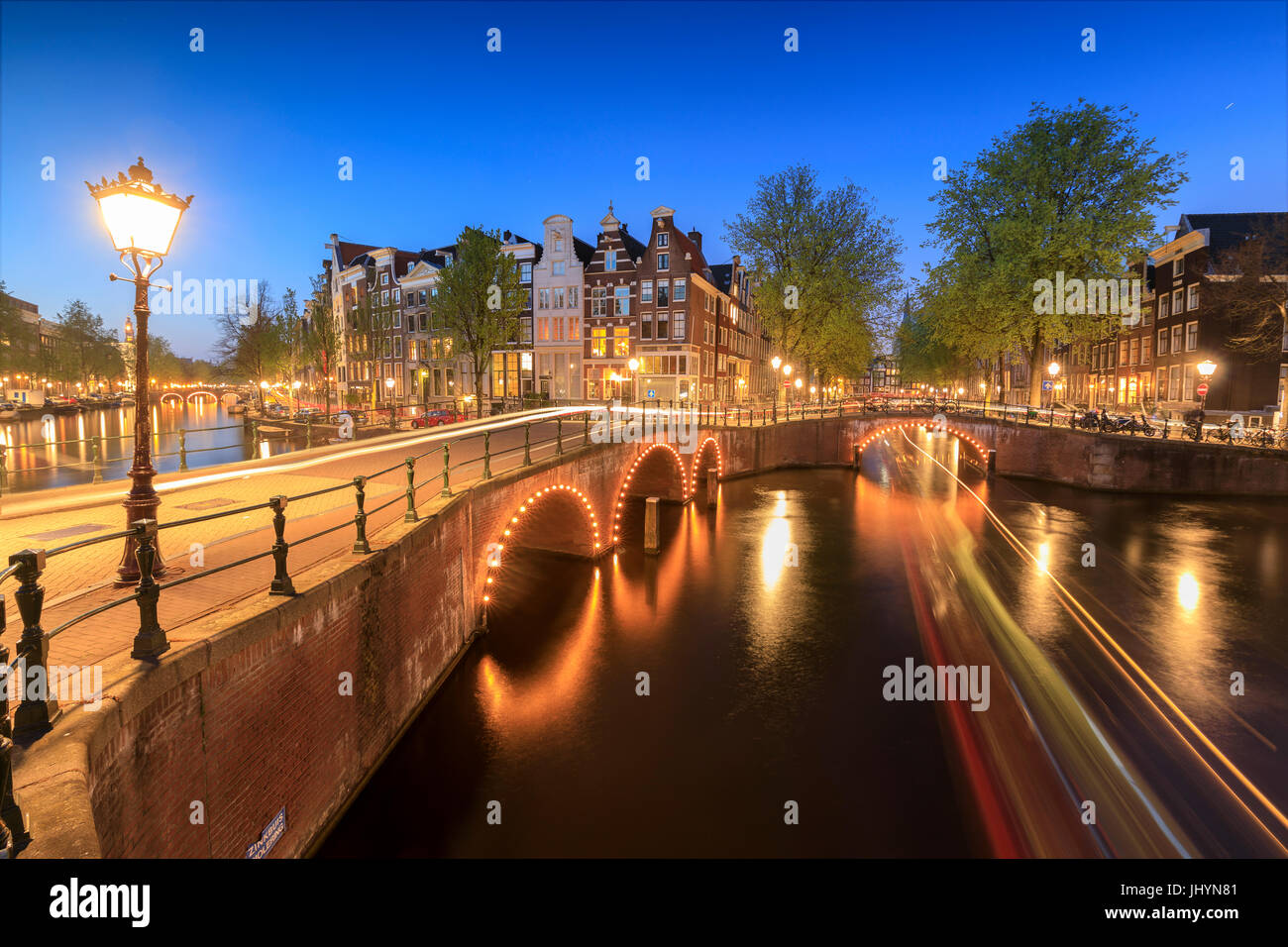 Le luci del tramonto su tipici palazzi e ponti si riflette in un tipico canale, Amsterdam, Olanda (Paesi Bassi), Europa Foto Stock