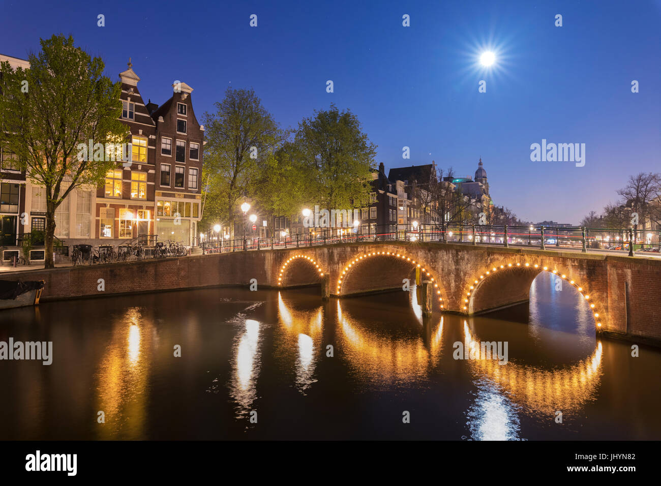 La luce del tramonto su tipici palazzi e ponti si riflette in un tipico canale, Amsterdam, Olanda (Paesi Bassi), Europa Foto Stock