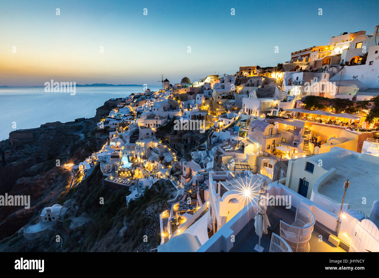 Il tramonto del bianco degli edifici in pietra e mulini a vento di Oia sulla punta di Santorini caldera, Santorini, Cicladi Grecia Foto Stock