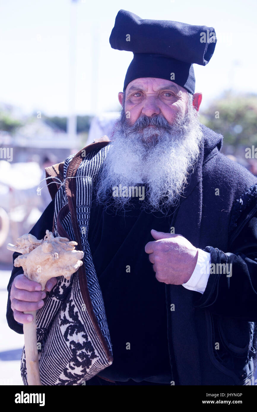 Uomo che indossa il tradizionale sardo Berritta hat e carring tradizionale sardo sac, Sant'Antioco, Sardegna, Italia Foto Stock