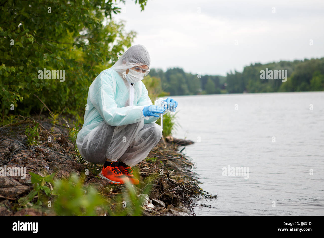 Giovani ambientalisti in tuta protettiva prende i campioni di acqua nel fiume Foto Stock