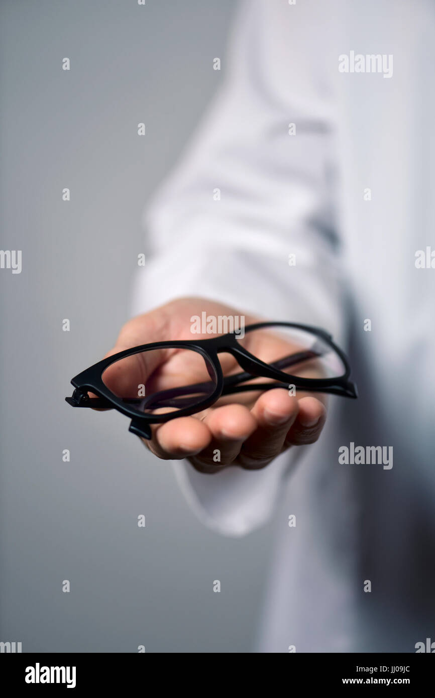 Primo piano di un giovane uomo ottico in un manto bianco di portare un paio di occhiali per l'osservatore Foto Stock