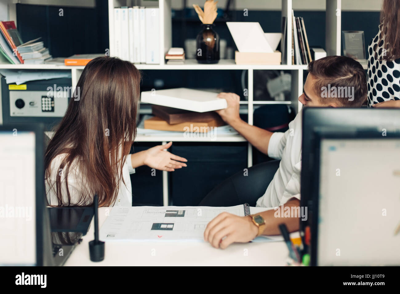 Coppia di giovani progettisti che lavorano presso un ufficio moderno, due colleghi per discutere il progetto di divertimento su un computer portatile, piccolo team di imprenditori sorridente e guardare Foto Stock