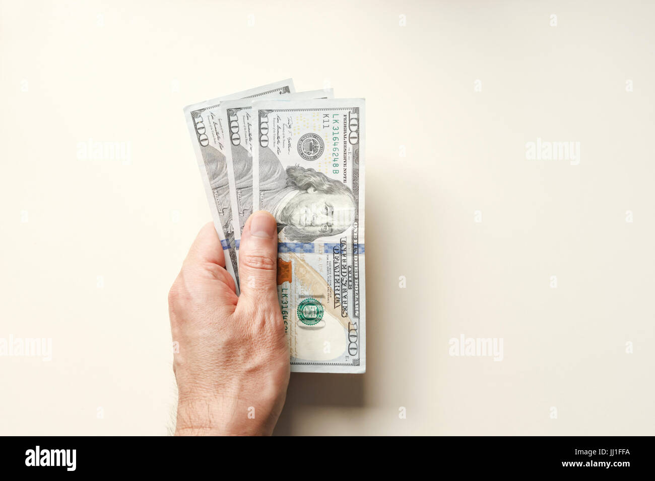 Mano che tiene isolate banconote da cento dollari su sfondo leggero: Finanza, risparmio, investimento e concetto di denaro. Foto Stock