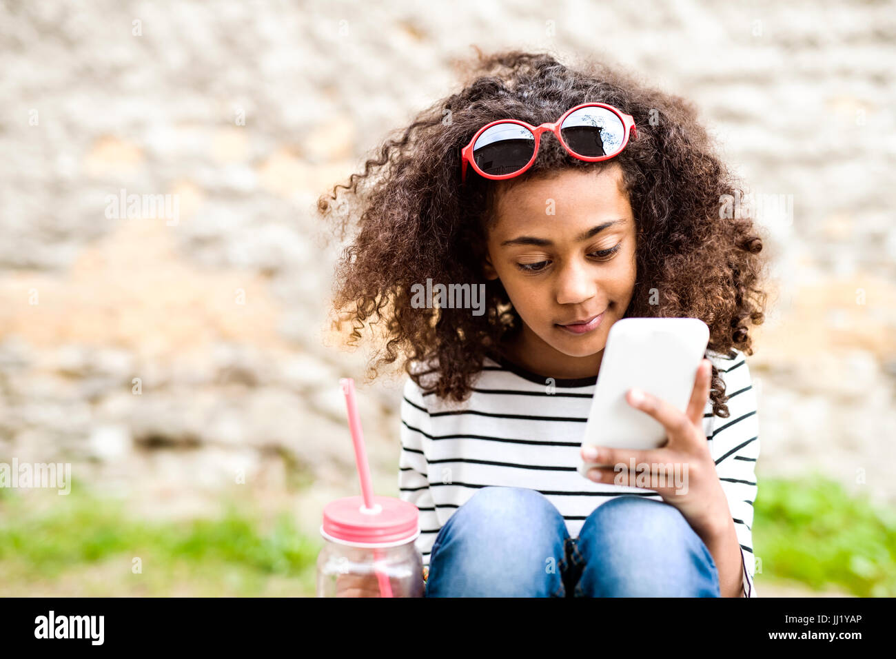 Bella African American Girl con lo smartphone e drink. Foto Stock
