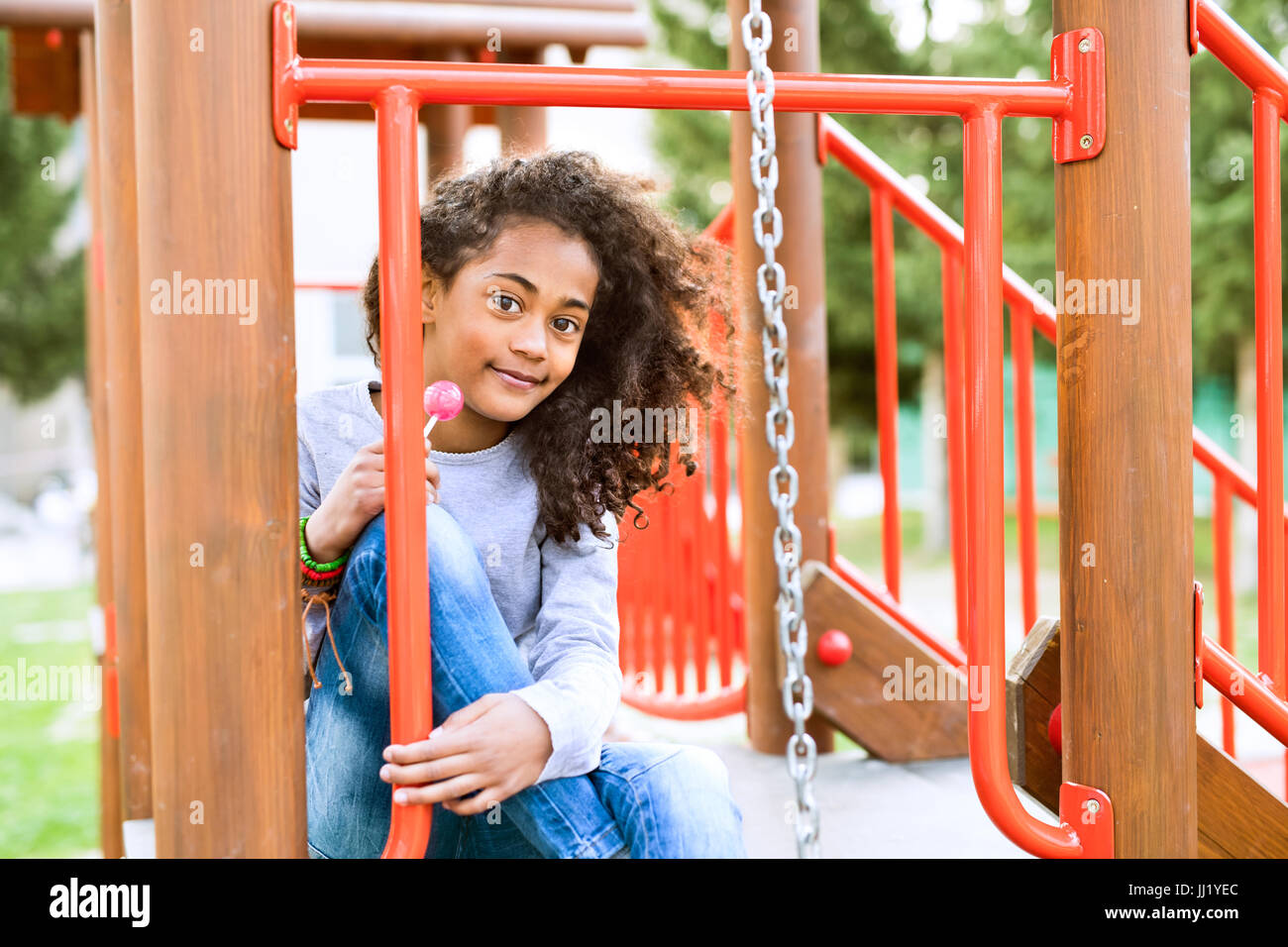 African American Girl sul parco giochi di mangiare lecca-lecca. Foto Stock