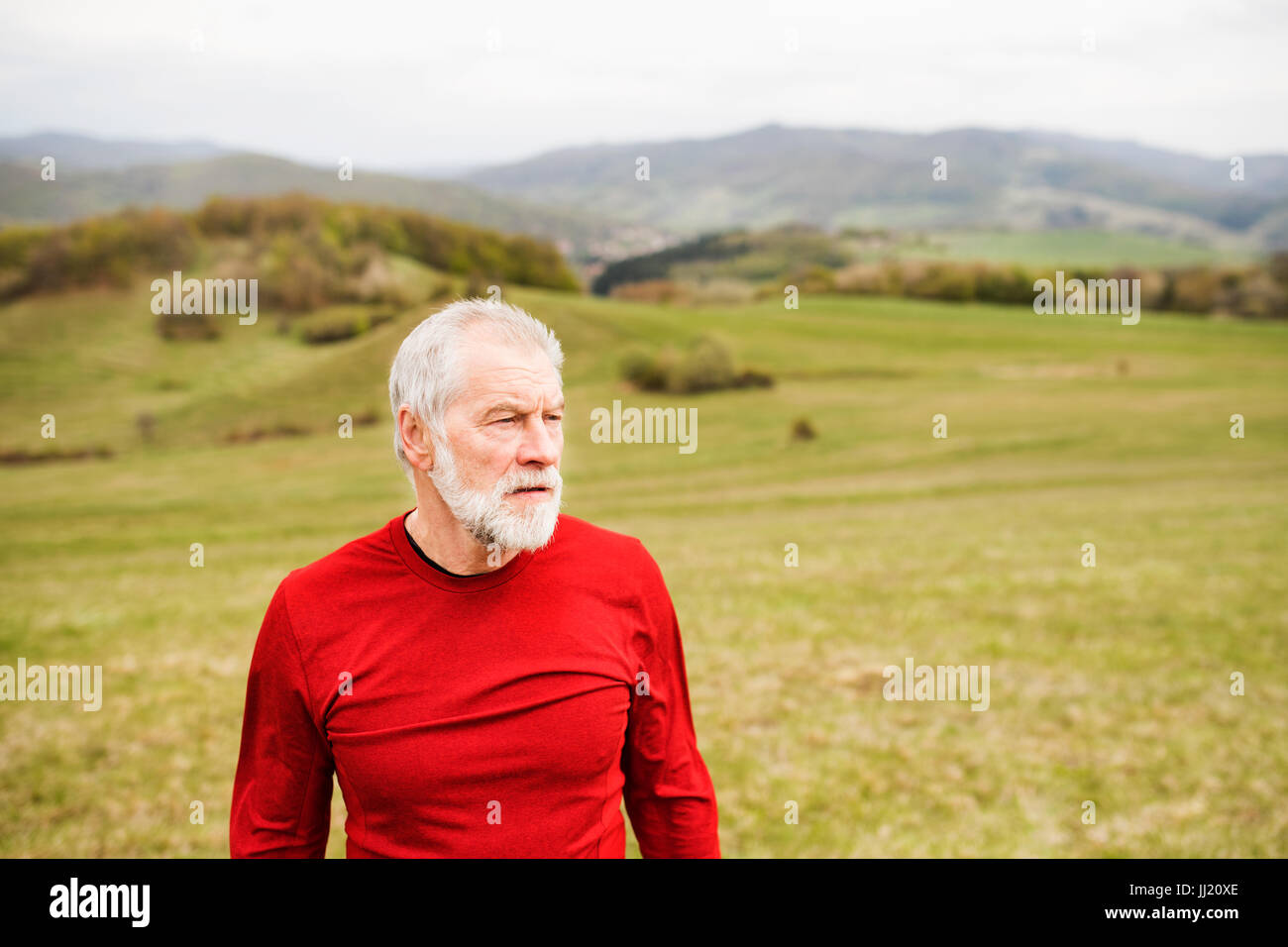 Active senior runner in felpa rossa in natura in appoggio. Foto Stock