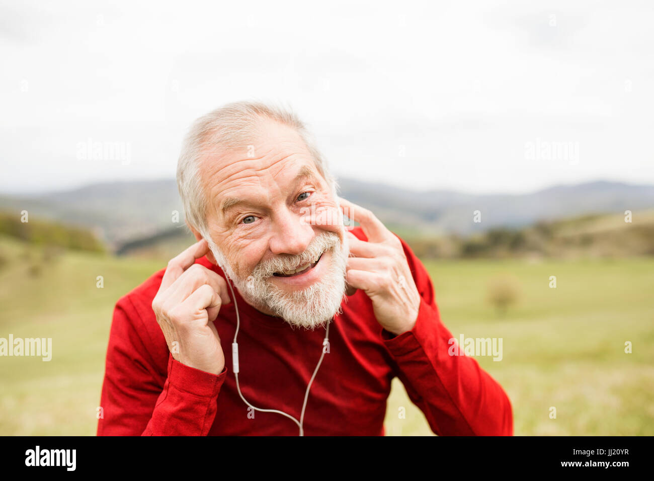 Active senior runner in natura in appoggio, ascoltando musica. Foto Stock