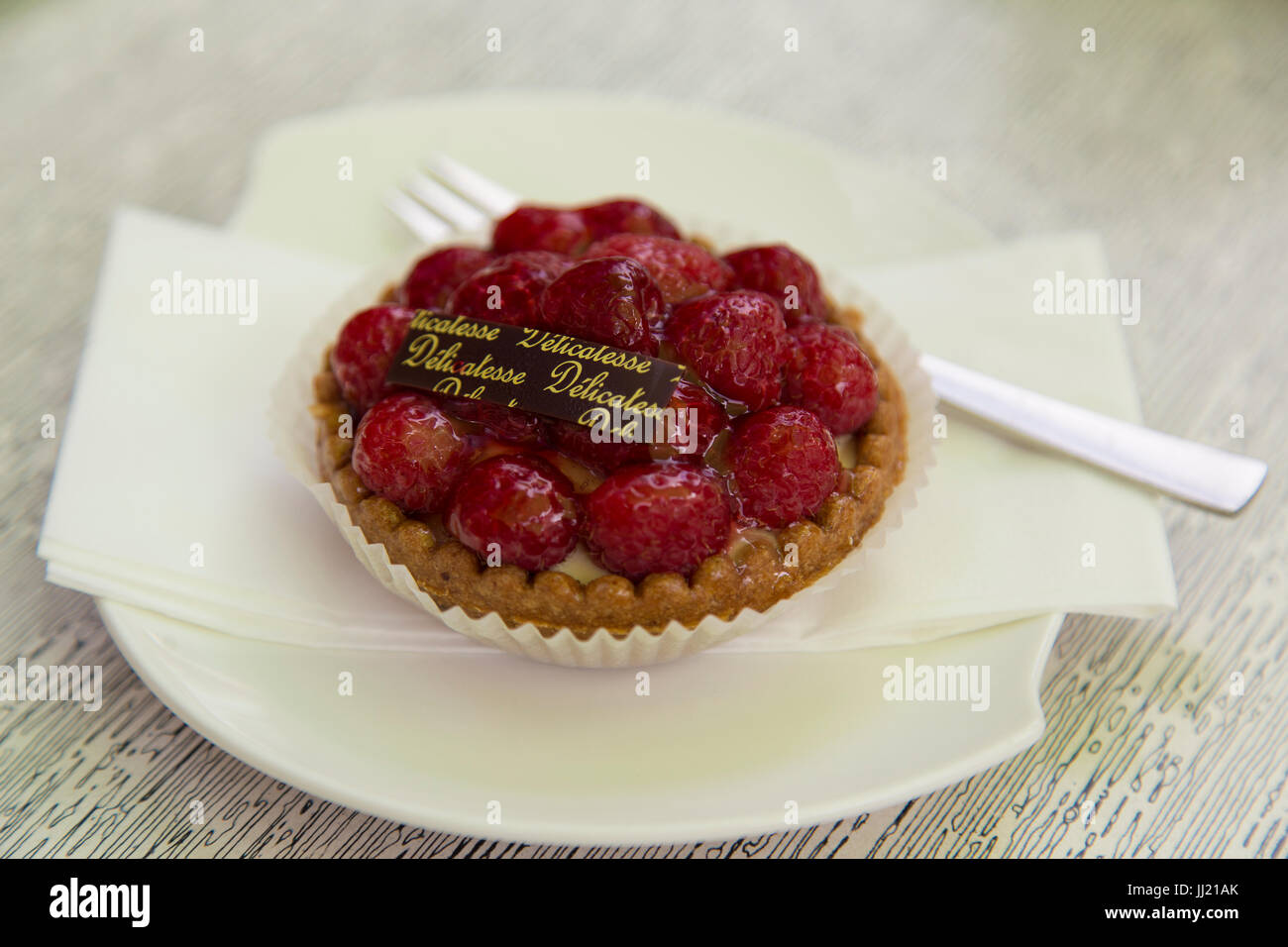 Piccolo Lampone tart su una piastra bianca con torta forcella. Foto Stock
