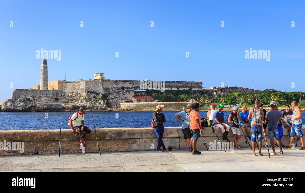 I pescatori sul Malecon, Castillo de los Tres Reyes del Morro dietro, Old Havana, Cuba Foto Stock