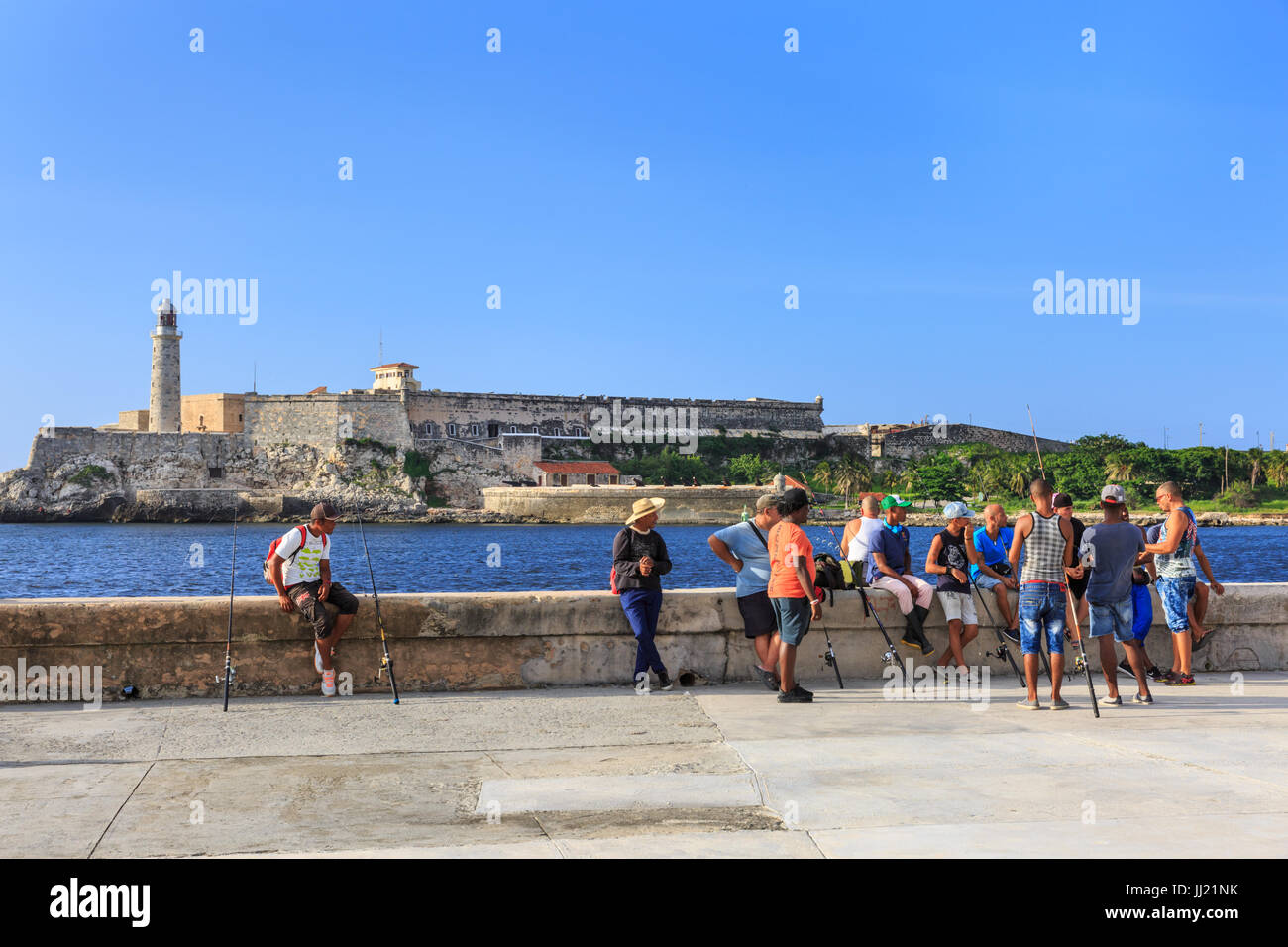 I pescatori sul Malecon, Castillo de los Tres Reyes del Morro dietro, Old Havana, Cuba Foto Stock