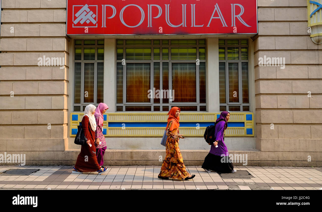 Quattro donne Malay a piedi lungo una strada nel centro cittadino di Kuala Lumpur in Malesia Foto Stock