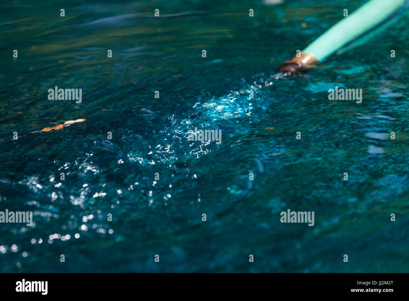 Il tubo flessibile di acqua lo svuotamento nel blu piscina d'acqua. Foto Stock