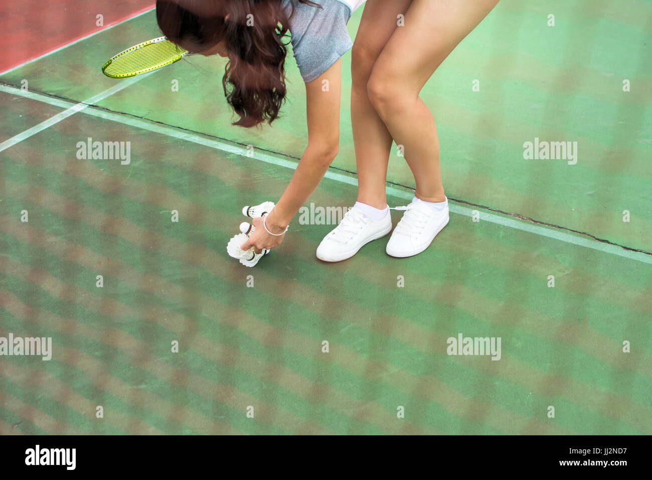 Ragazza la raccolta di badminton palla dietro la rete Foto Stock