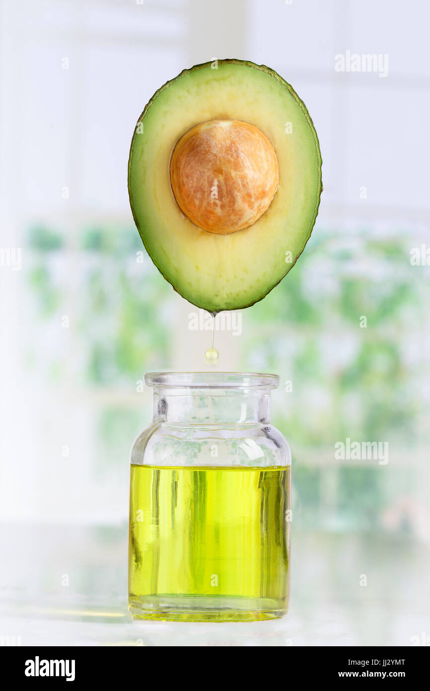 Fresco e di avocado olio cade in una bottiglia su bianco Foto Stock