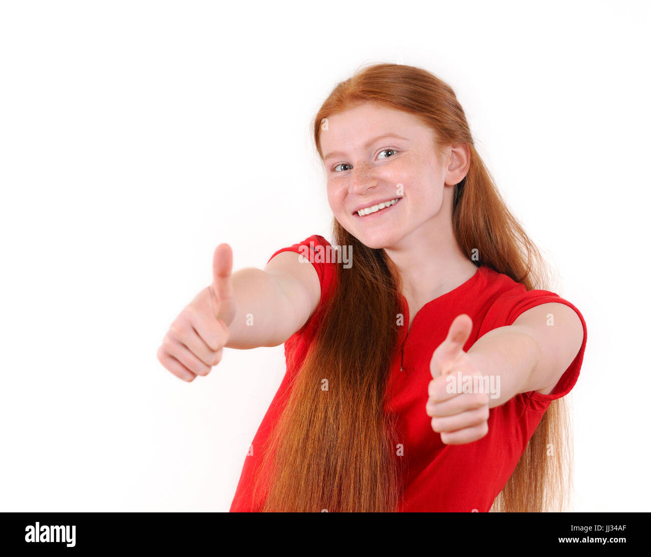 Capelli rossi ragazza adolescente in una maglietta rossa che mostra un pollice in su su sfondo bianco. Sorridenti lifestyle persone concetto. Le emozioni umane. Redhair naturale Foto Stock
