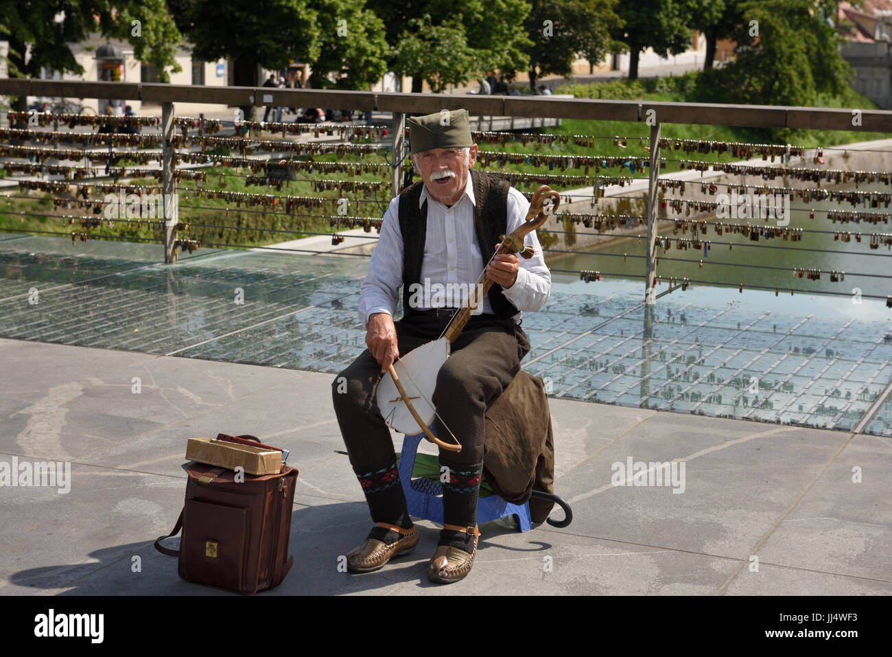 Maschio vecchio musicista di strada suonando e cantando un singolo Gusle a corda con arco sulla macelleria ponte sopra il fiume Ljubljanica Ljubljana Slovenia Foto Stock