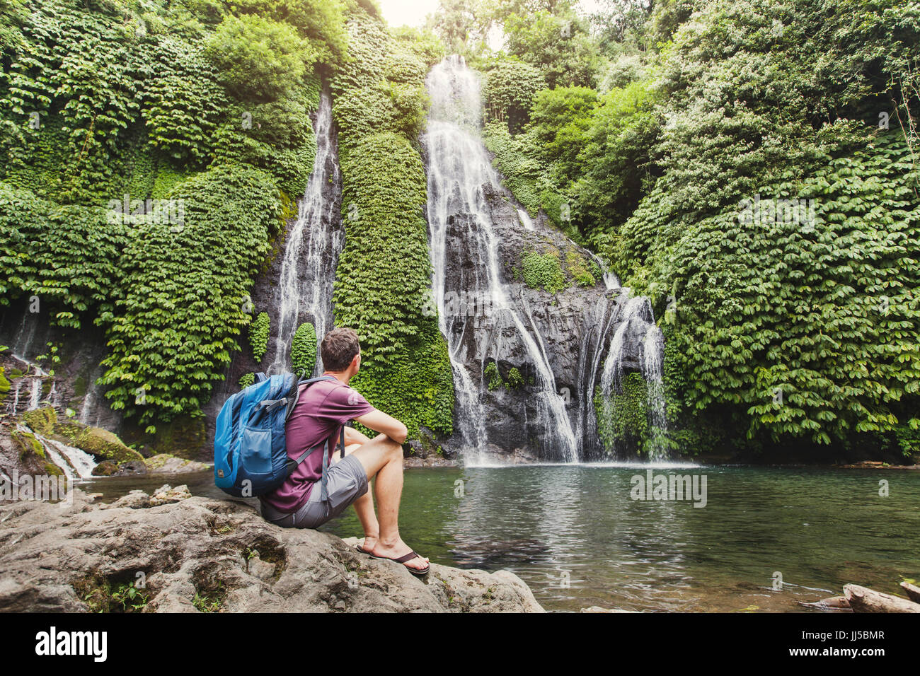 Tourist backpacker guardando a cascata in Bali Foto Stock