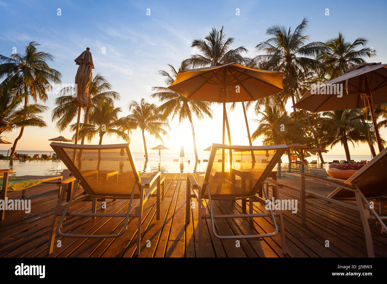 Due sedie a sdraio vicino alla piscina al tramonto nella spiaggia di lusso hotel sull isola tropicale Foto Stock