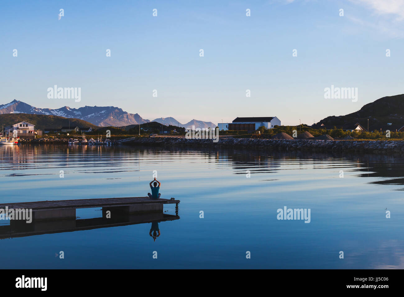 Lo yoga e la meditazione di sfondo, silhouette dell'uomo rilassante sul molo sul lago Foto Stock