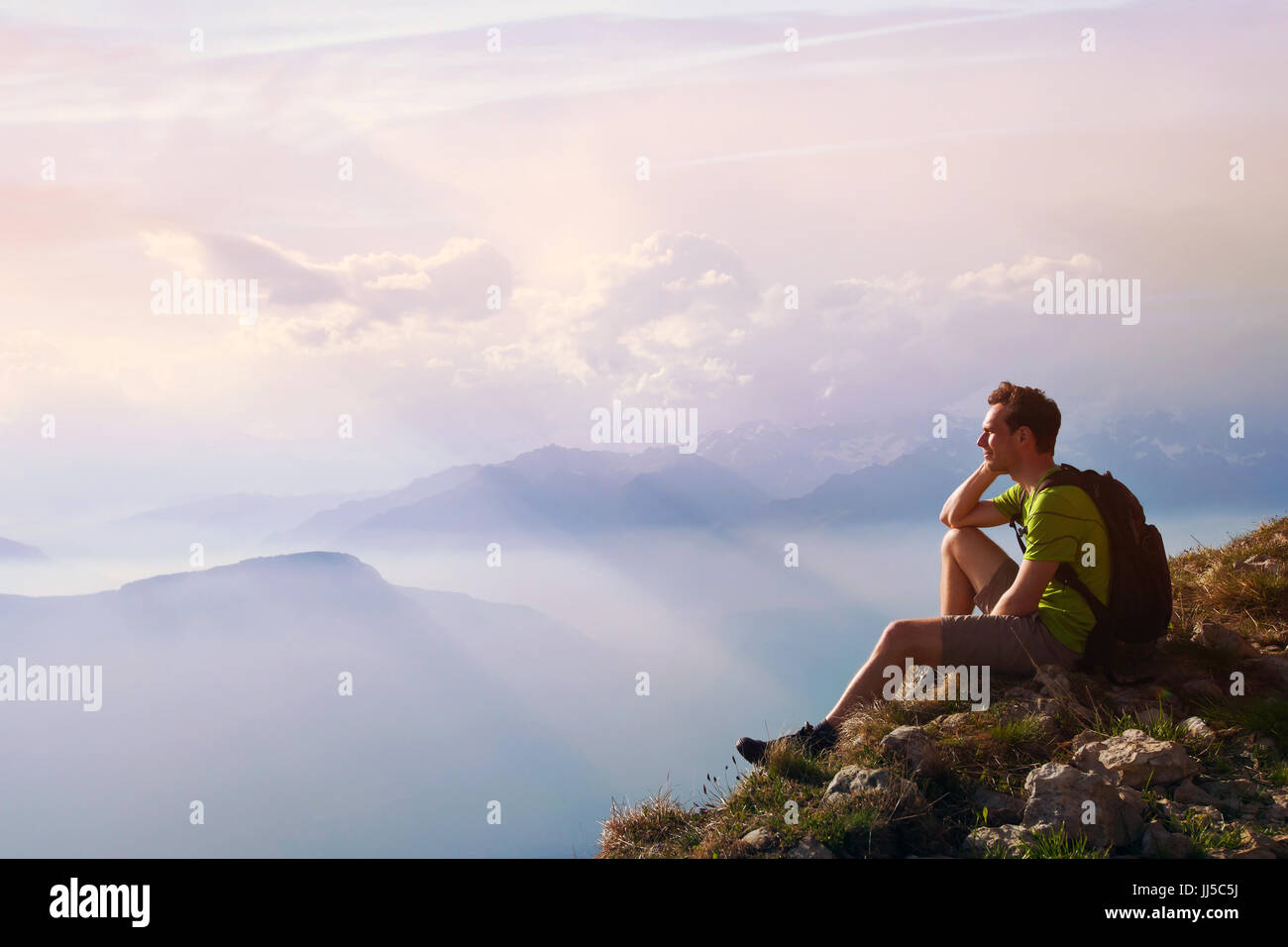 Uomo seduto sulla cima della montagna, conseguimento o opportunità concetto, escursionista guardando avanti sul bellissimo paesaggio panoramico Foto Stock