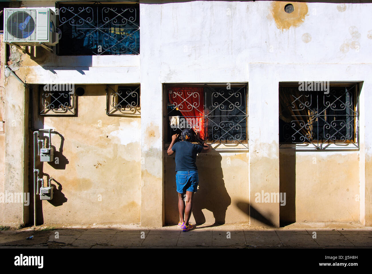 Donna sorge sul lato di una strada nella vecchia Havana, Havana, Cuba Foto Stock