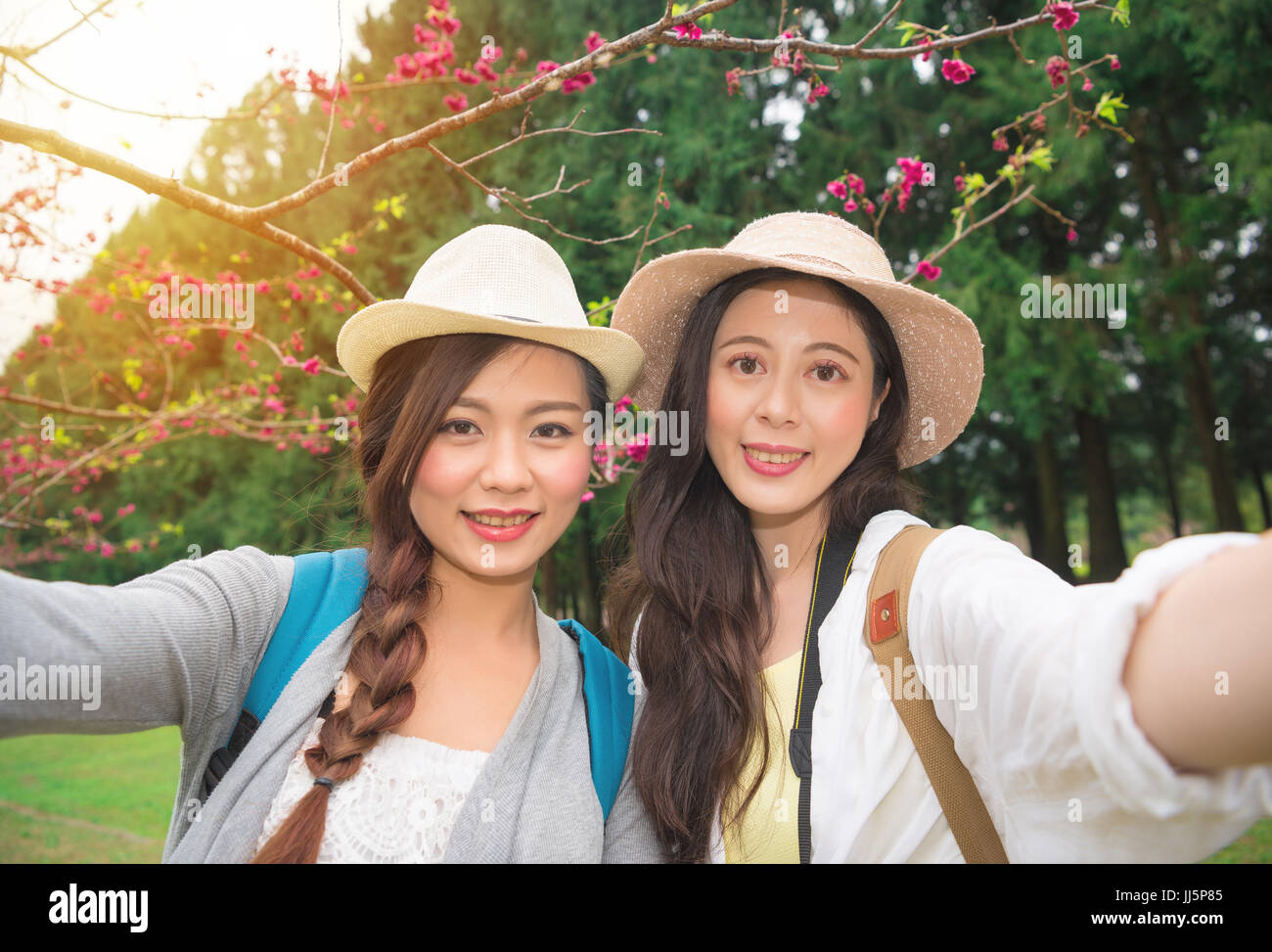 Korea Travel prendere foto con la fioritura dei ciliegi. Visite turistiche amiche divertirsi utilizzando la fotocamera dello smartphone tenendo selfie autoritratto sorridendo felice in Foto Stock