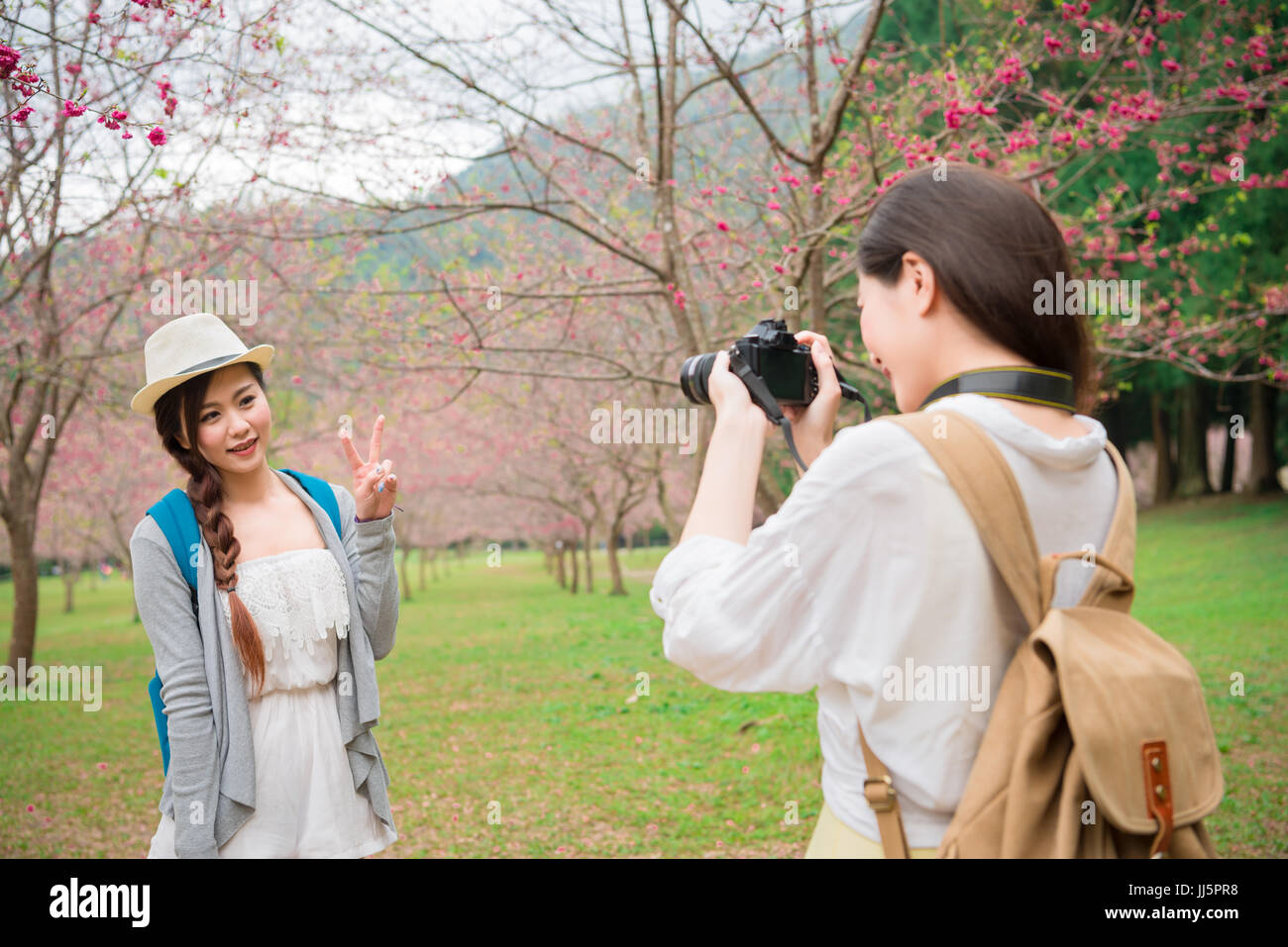 Gli amici di scattare le foto divertendosi lifestyle godendo guardando la fioritura dei ciliegi nel parco sakura outdoor activity. Donna asiatica prendendo fotografie con la camma Foto Stock