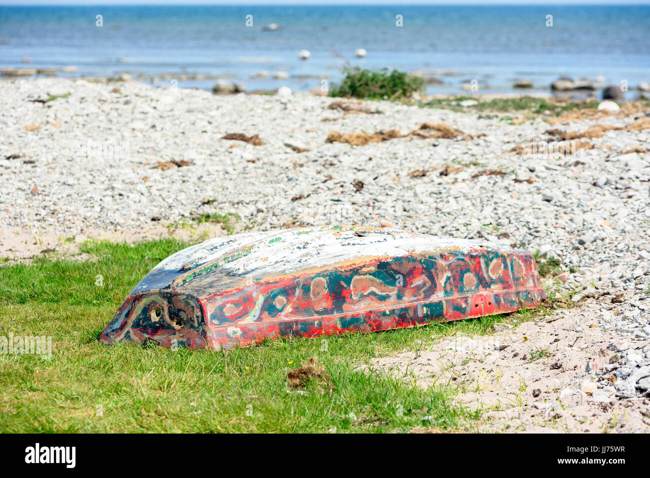 Abbandonato e rotto piccolo canotto giacente capovolto sulla spiaggia di calcare. Foto Stock