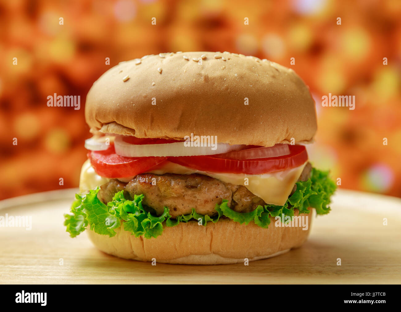 Burger sul piatto di legno con sfondo arancione Foto Stock