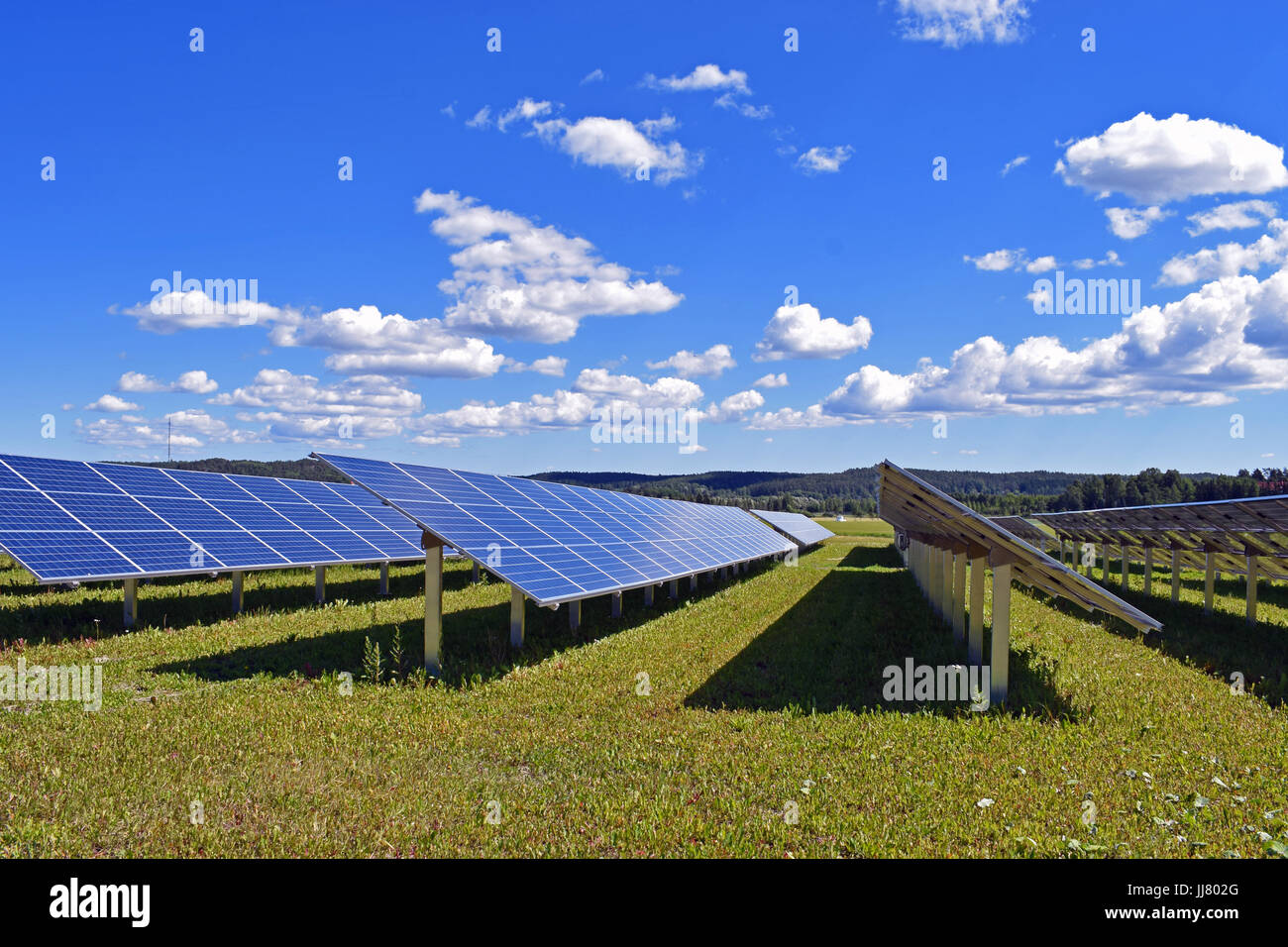 Pannelli solari sul campo. Cielo sereno con poche piccole nuvole sullo sfondo. Foto Stock
