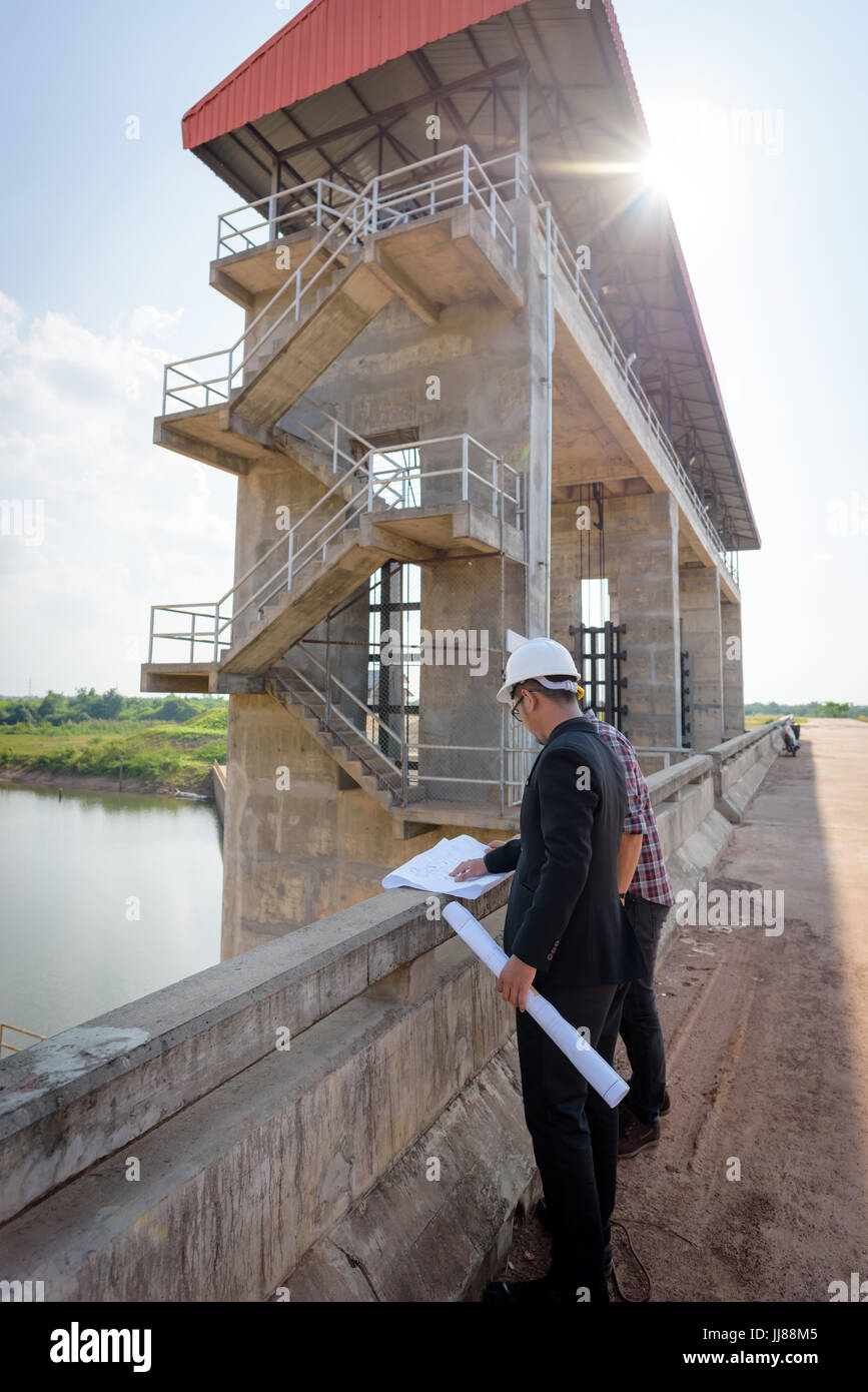 Gli uomini d' affari incontro con gli ingegneri e i supervisori sono di lettura permanente il blueprint sul sito di costruzione. Foto Stock