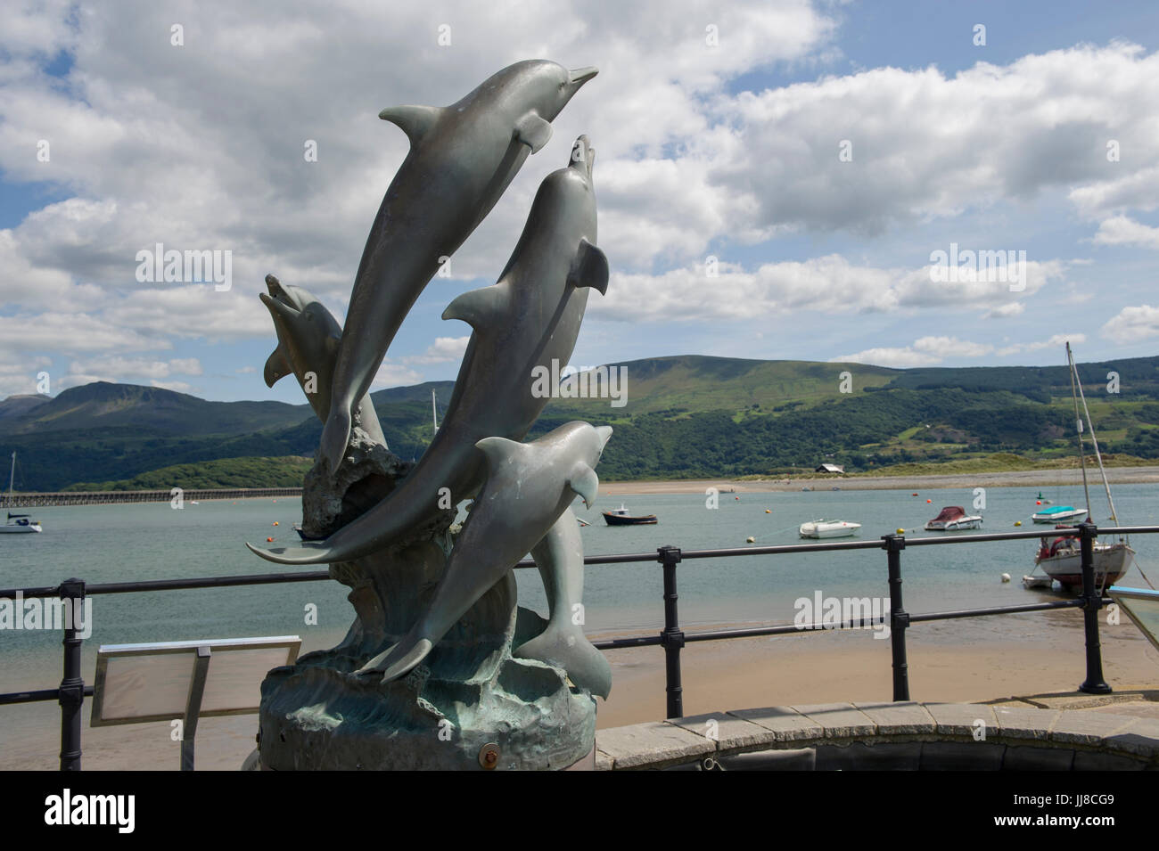 La statua di delfini saltando su theAfon Mawddach harbor, nella città balneare di Barmouth in Galles Foto Stock