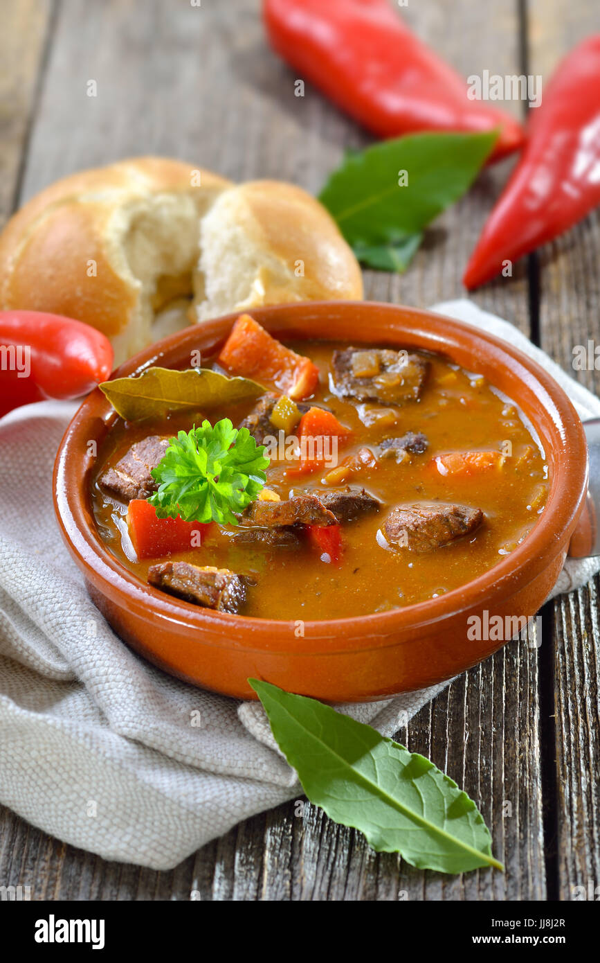 Ungherese calda zuppa di gulasch servito in una ciotola di ceramica con un nuovo rotolo Foto Stock