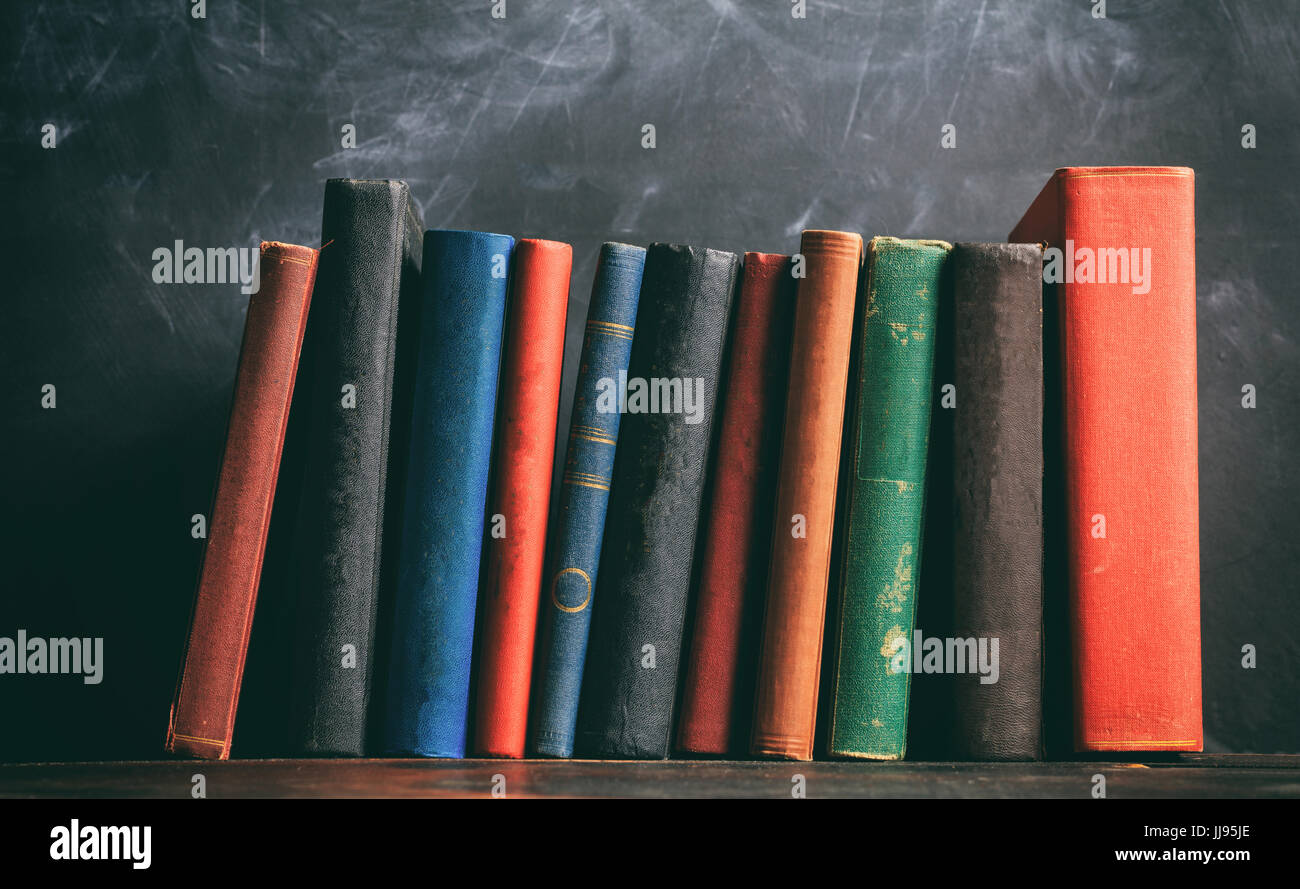 Il concetto di istruzione. Vecchi libri sullo sfondo della lavagna Foto Stock