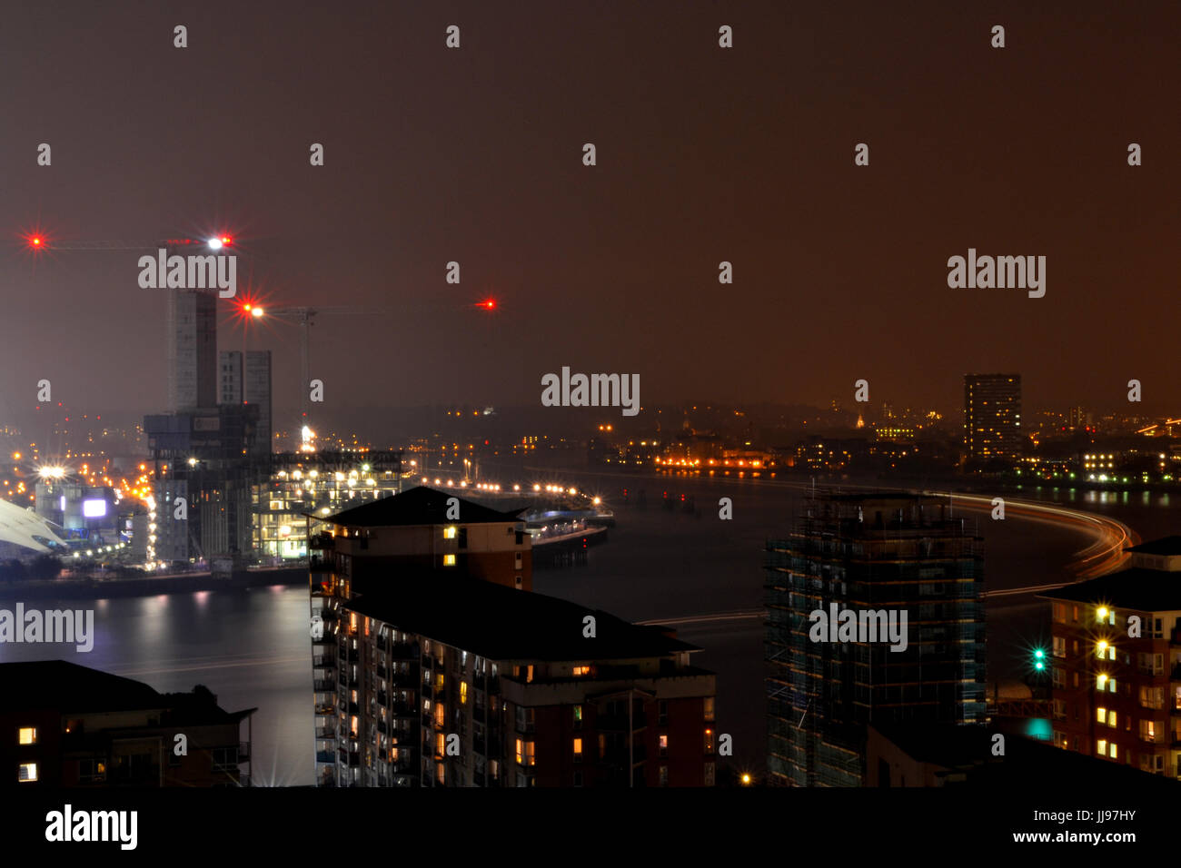 Luce-sentiero del traghetto passando l'arena O2 lungo il fiume Tamigi, Londra, con luci della città di notte Foto Stock