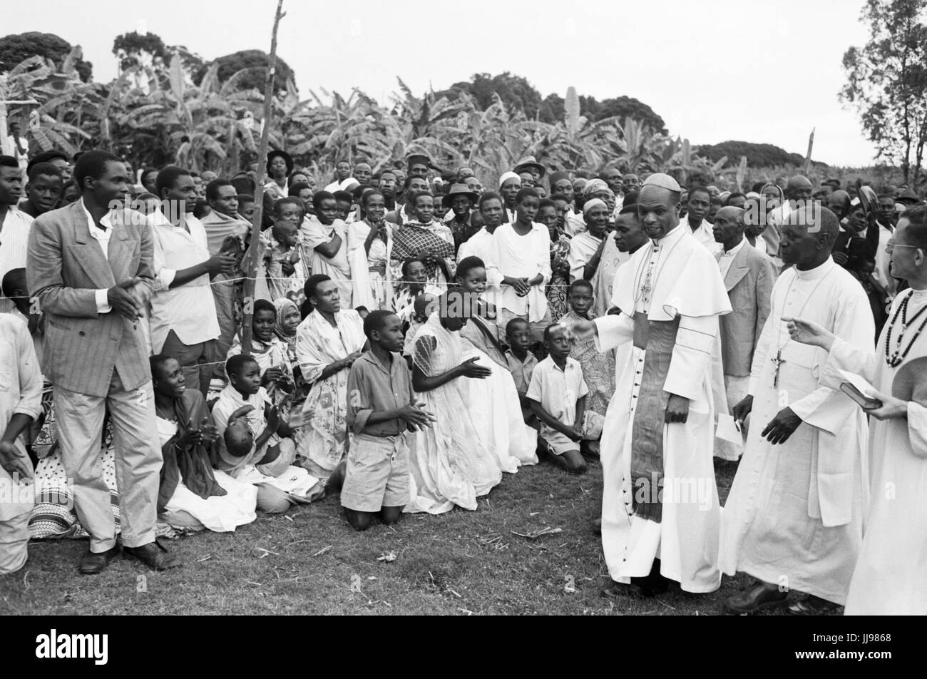 Il Cardinale Laurean Rugambwa incontro gli abitanti di un villaggio in corrispondenza di un evento esterno. La posizione è Tanganika (Tanzania), 1960. Foto Stock