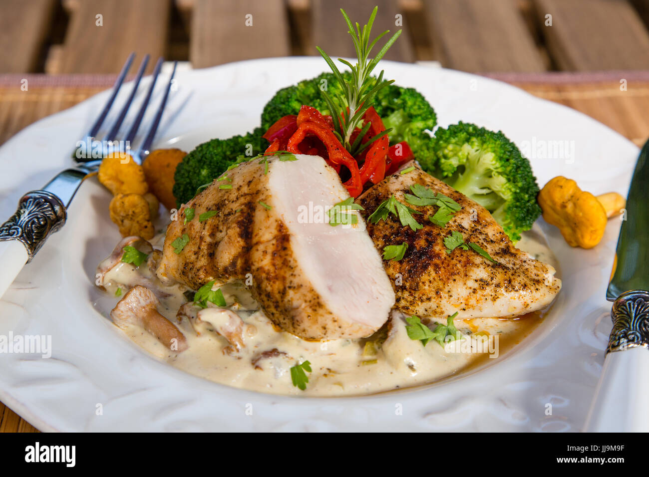 Pollo alla griglia, salsa alla panna con funghi finferli, broccoli e arrostito peperoni rossi. sana e bilanciata concetto alimentare. Foto Stock