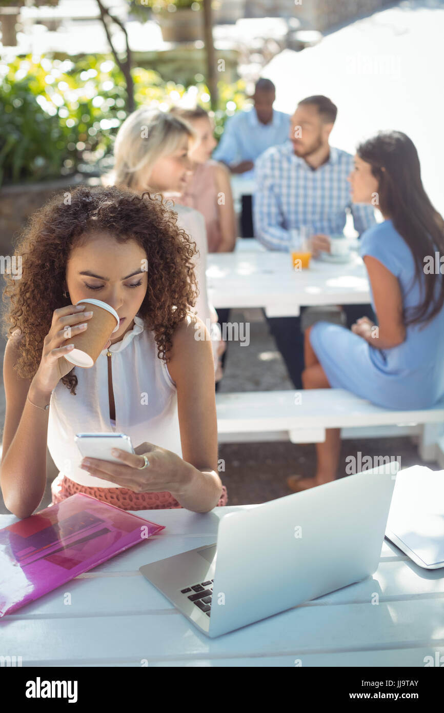 Bella donna usando il cellulare mentre un caffè nel ristorante Foto Stock